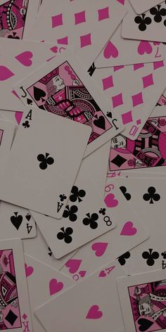 many playing cards are laying on top of each other, all pink and black colors