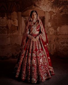 a woman in a red and gold bridal gown standing with her hands on her hips