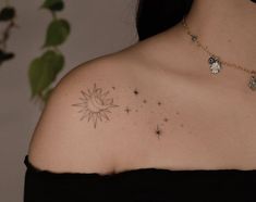 a woman wearing a black top has a small tattoo on her shoulder and is looking at the sun