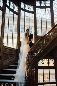 a bride and groom standing on the stairs in front of an ornate glass dome at their wedding