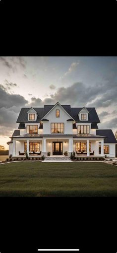 a large white house with lots of windows and grass in the front yard at dusk