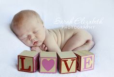 a baby laying on top of blocks that spell out love