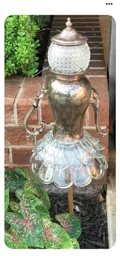 a glass vase sitting on top of a metal stand next to a green planter