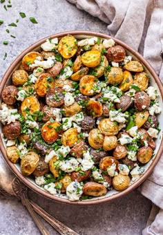 a bowl filled with potatoes and spinach on top of a gray table next to silverware