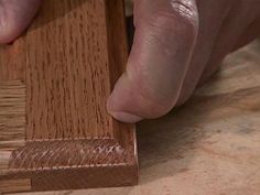 a person using a piece of wood to work on a piece of wooden flooring