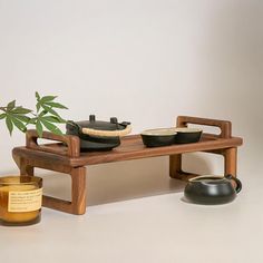 a wooden table topped with a potted plant next to a teapot and candle