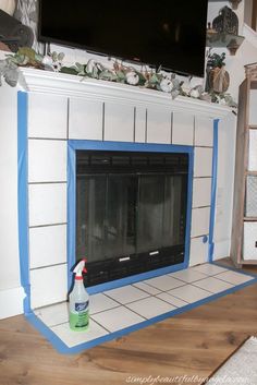 the fireplace is painted white and has blue trim around it, with a bottle of cleaner next to it