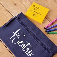 a blue bag with writing on it next to colored pencils