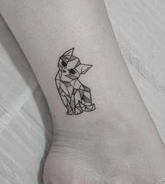 a small cat tattoo on the ankle is shown in black and grey colors, with geometric shapes