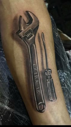 a black and white photo of a wrench and screwdriver tattoo on the arm