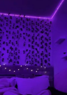 a bed in a room with purple lights on the headboard and wall behind it