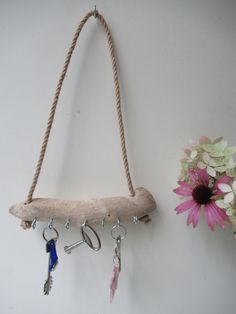 a wall hanging with several keys and some flowers on the other side, next to a pink flower