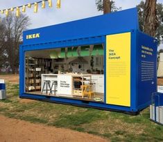 a blue and yellow container sitting on top of a grass covered field next to trees