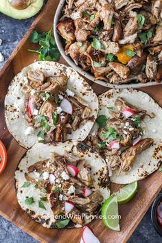 three tacos with meat and vegetables on a cutting board