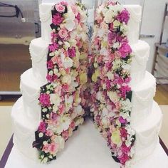 two tiered wedding cake with pink and white flowers on the side, cut in half