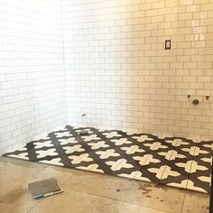 the floor is being laid out in the shower room with white tiles and black grout