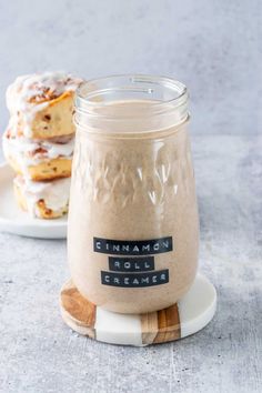 cinnamon roll cream in a glass jar on a plate next to a stack of doughnuts