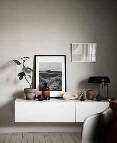 a white shelf with some plants and pictures on it