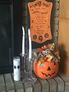 a pumpkin sitting on top of a mantle next to two candles and a glass vase