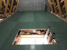 an unfinished room with green flooring and wooden beams