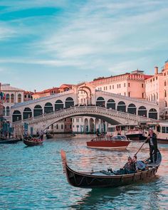 two gondolas in front of a bridge with people riding on one and another boat