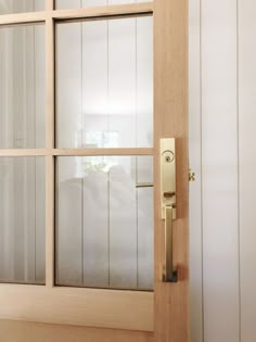 an open wooden door with glass panels on the outside and inside, in front of a white wall