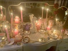 a table topped with lots of candles next to a dresser covered in plates and dishes