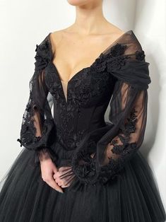 a woman wearing a black dress with sheer sleeves