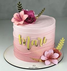 there is a pink cake with flowers on the top and gold lettering that says happy