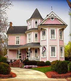 a large pink house with white trim on the front and side of it's roof