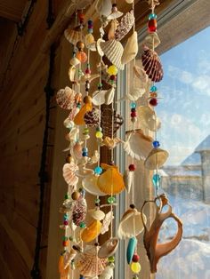 a wind chime hanging from the side of a window with seashells on it