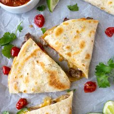 three quesadillas cut in half with salsa and limes on the side