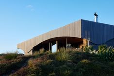 a house on top of a hill with grass and bushes around it's edges