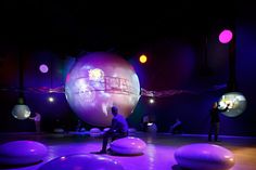 some people are sitting on large balls in the middle of a room with purple lighting