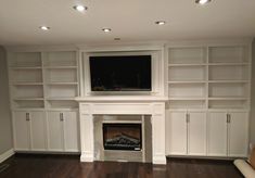 an empty living room with built in bookshelves and fireplace