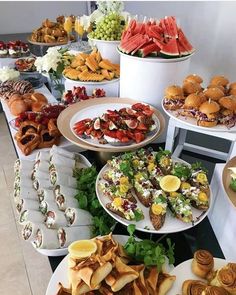 a table filled with lots of different types of food on plates and serving trays