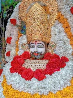 the statue is decorated with flowers and feathers on it's head, as well as an elaborate crown