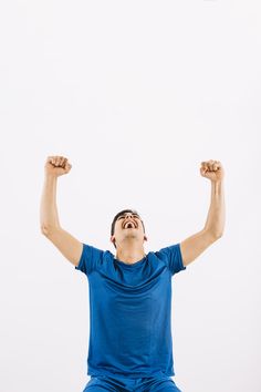 a man is sitting on the ground with his arms raised up in triumph while holding a frisbee above his head