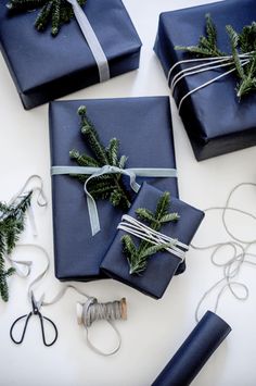 presents wrapped in dark blue paper and tied with twine, pine needles and ribbons