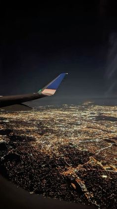 an airplane wing flying over a city at night