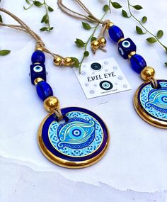 two blue and gold necklaces with an evil eye design on the front, hanging from a string