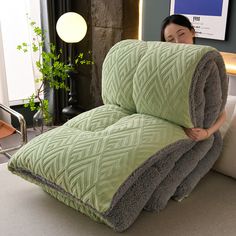 a woman sitting on a couch covered in blankets with her head resting on the pillow