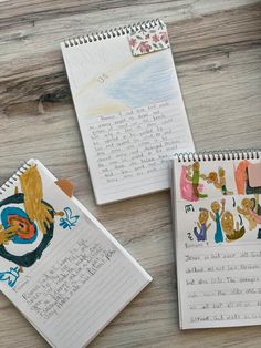 three children's notebooks with drawings on them