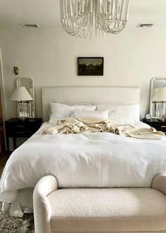 a bedroom with a bed, chair and chandelier