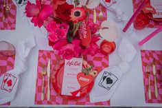 a table set for valentine's day with flowers and cards