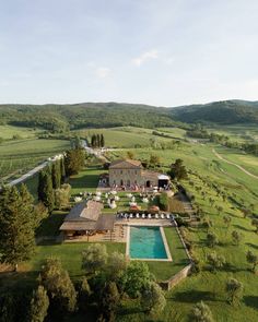 an aerial view of a large house in the middle of a field with a swimming pool