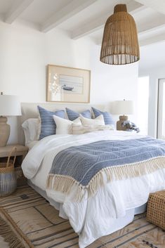 a bedroom with a large bed and wicker lamps hanging from the ceiling above it