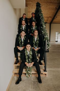 a group of men in suits sitting on steps with greenery around their neckties