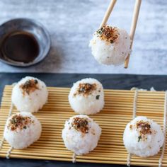 rice balls are being served with chopsticks on a bamboo mat