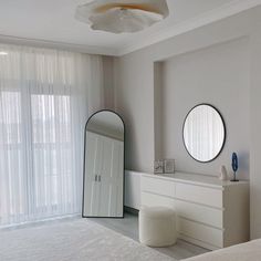 a bedroom with a bed, dresser and round mirrors on the wall next to it